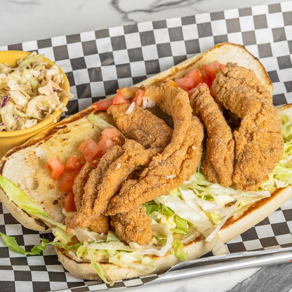 Mic's Kitchen fried fish po'boy with lettuce, tomatoes, and a side of coleslaw.