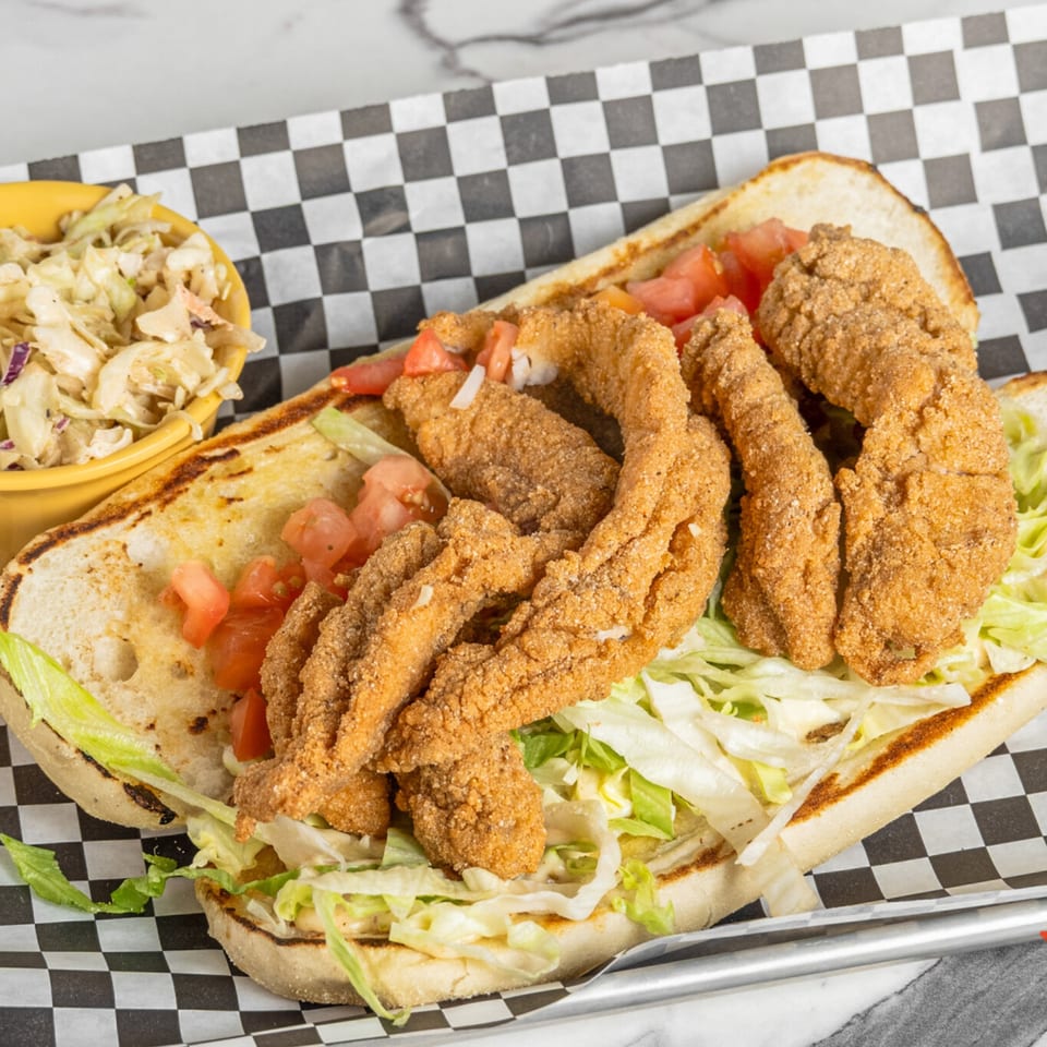 Mic's Kitchen fried fish po'boy with lettuce, tomatoes, and a side of coleslaw.